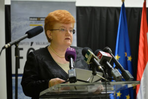 a woman is giving an interview surrounded by microphones